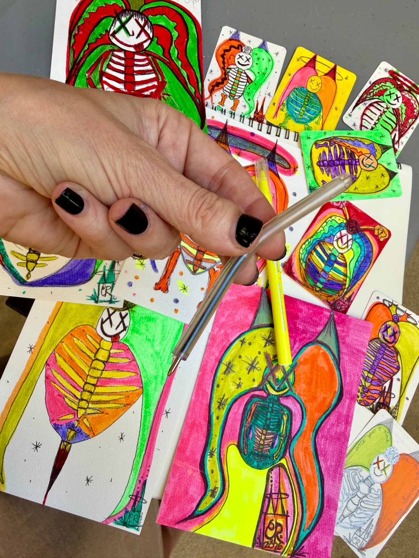 Channon holding the tiny bendy psychiatric safety pen over the Skeleton Psychosis artwork